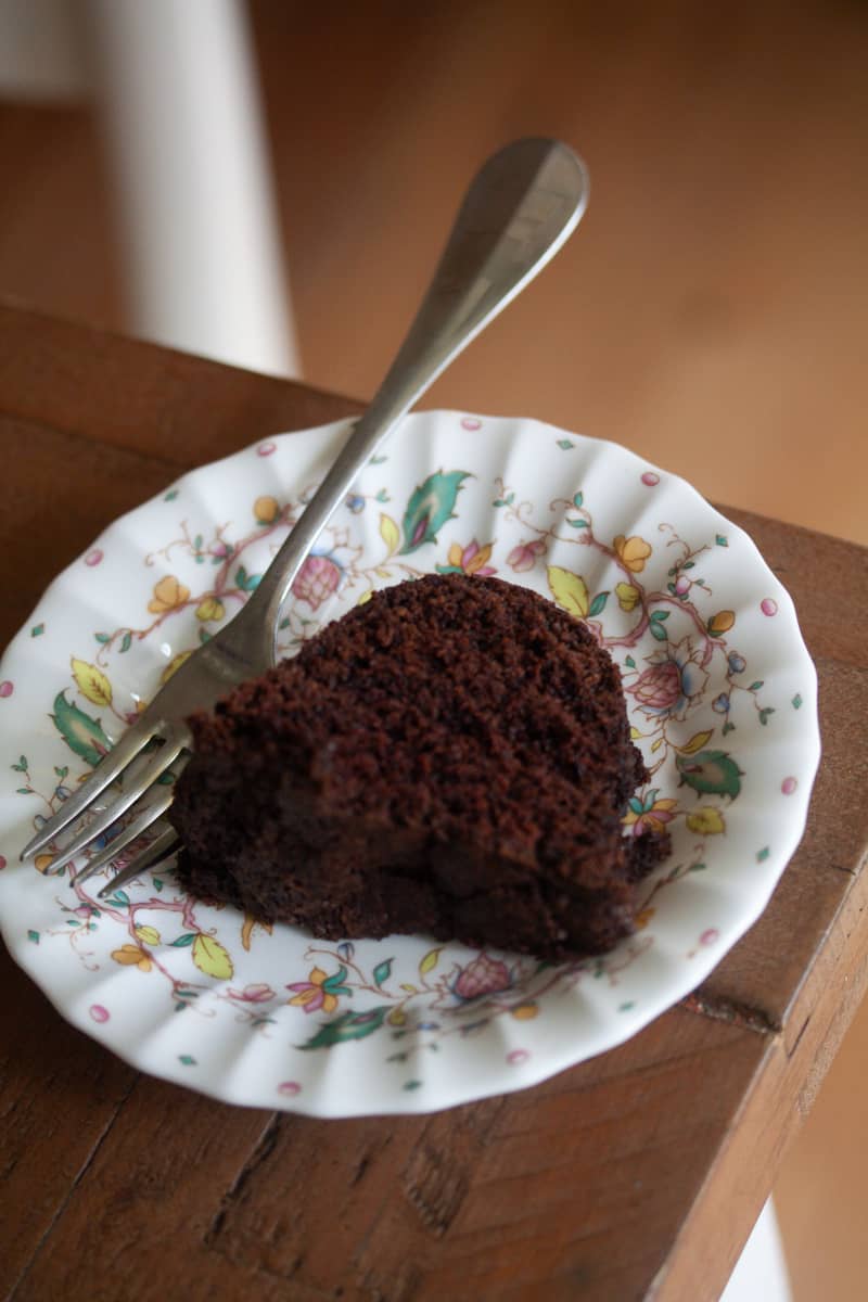 A fork rests alongside a plate holding a slice of vegan chocolate bundt cake.