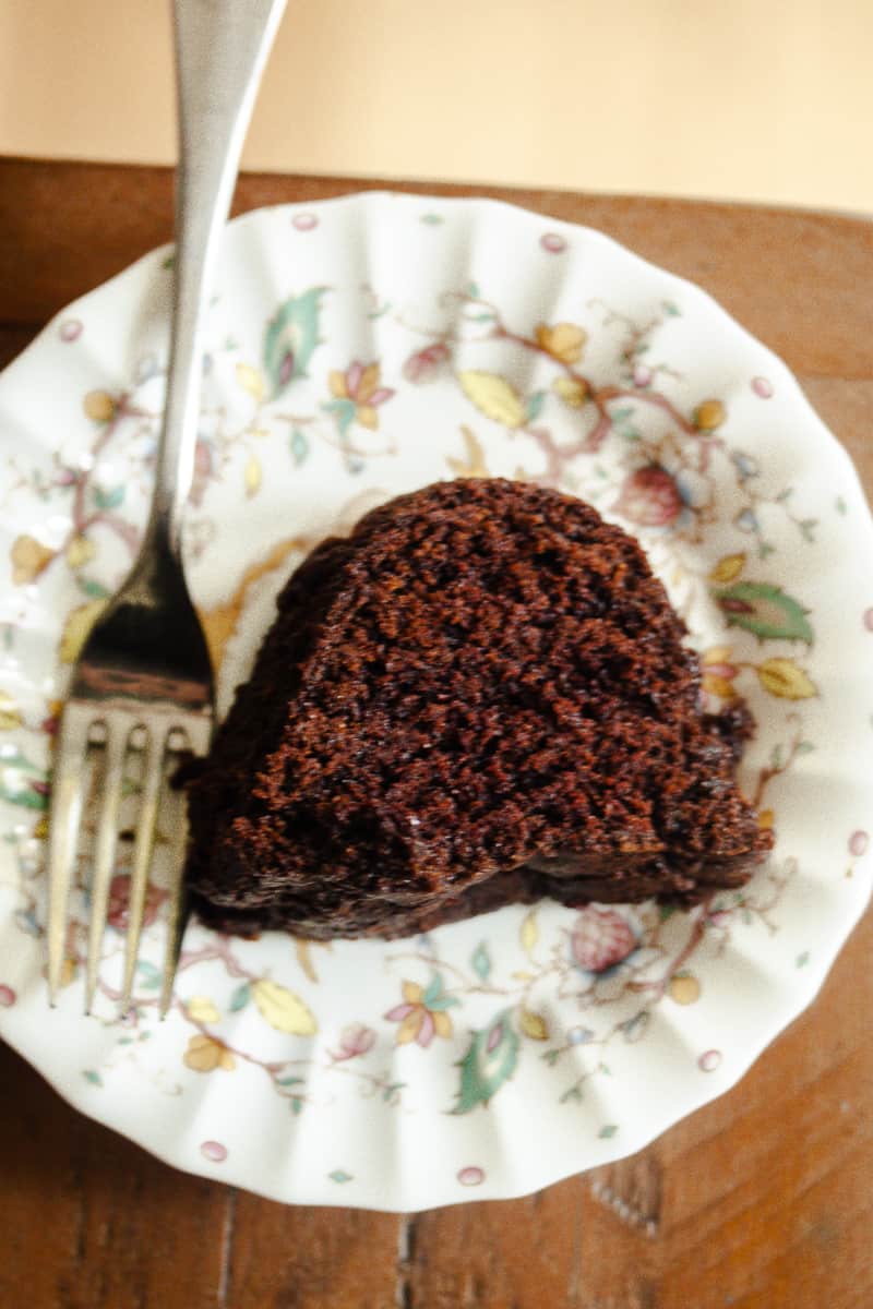 A close up of a slice of vegan chocolate bundt cake on a plate with a fork.