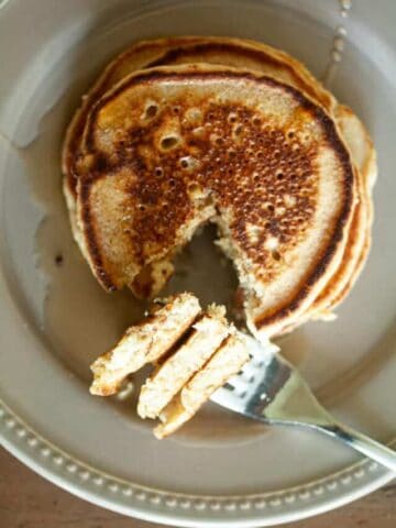 A fork picks up a piece of an oat flour pancake.