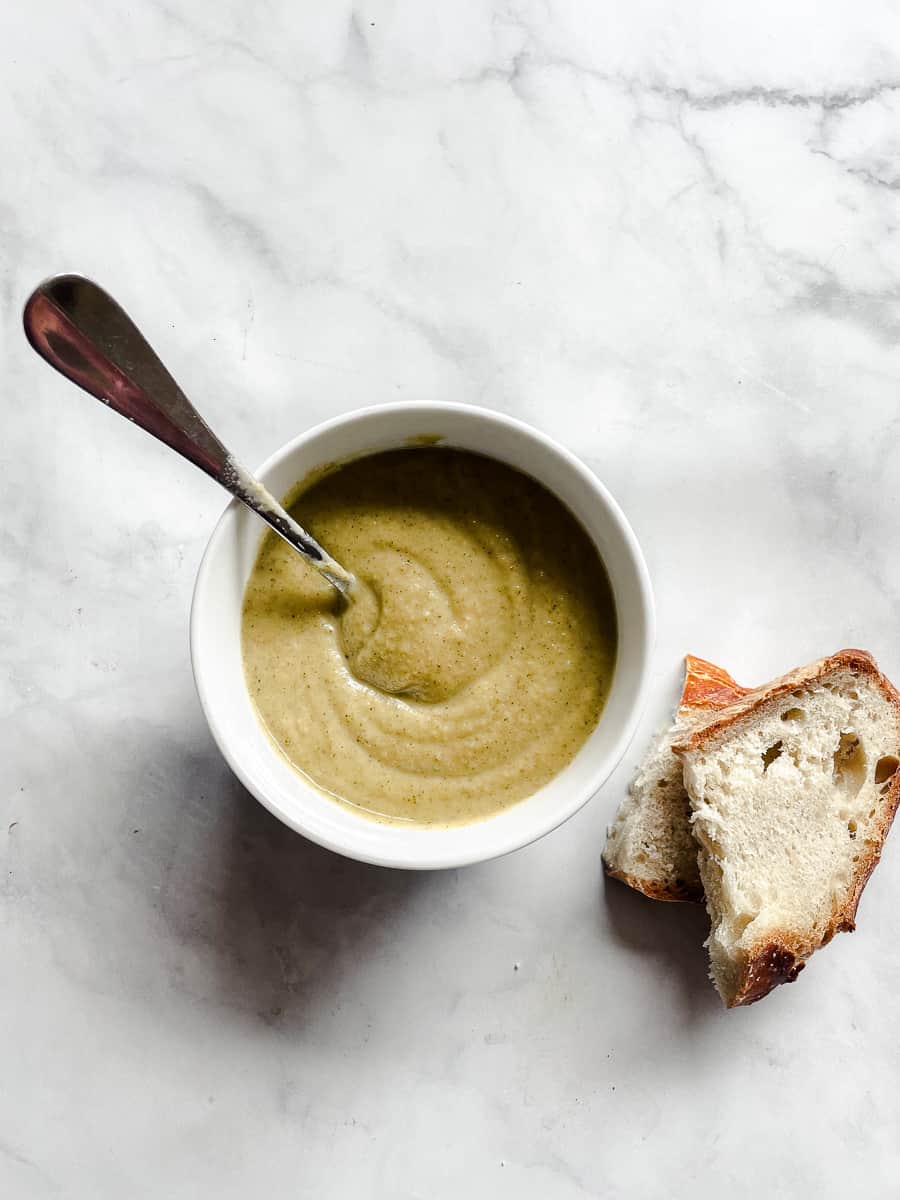 A bowl of broccoli soup with bread.