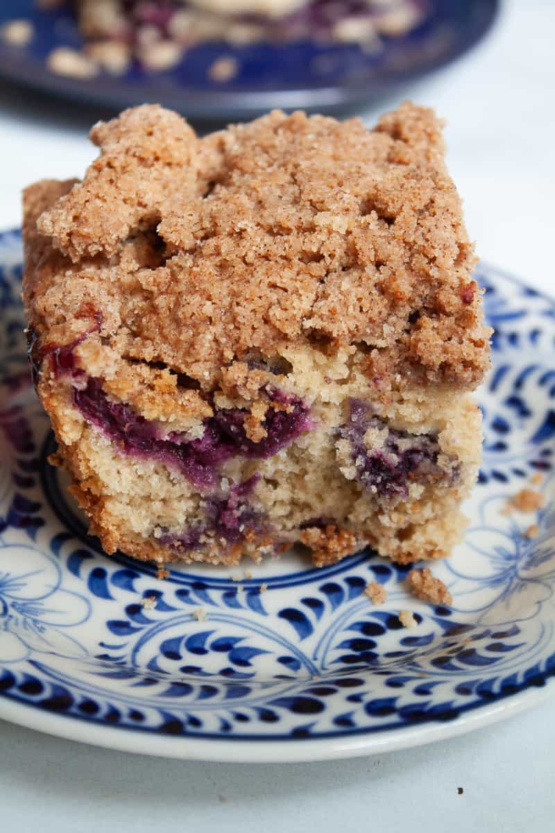A crumble-topped piece of blueberry coffee cake on a plate.