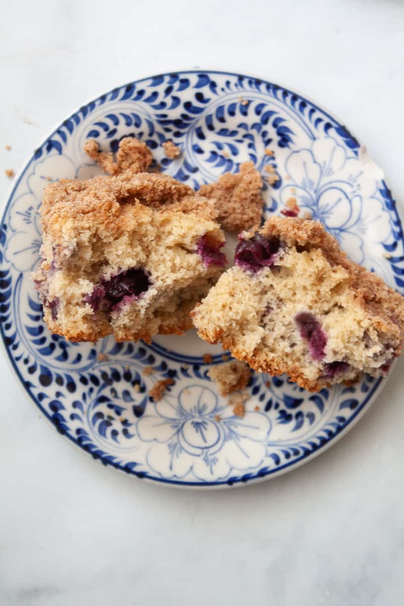 A piece of blueberry coffee cake split in half on a plate.