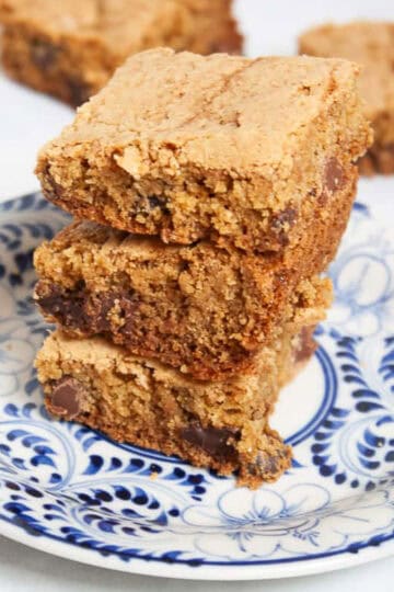 A stack of gluten free chocolate chip cookie bars on a blue and white plate.