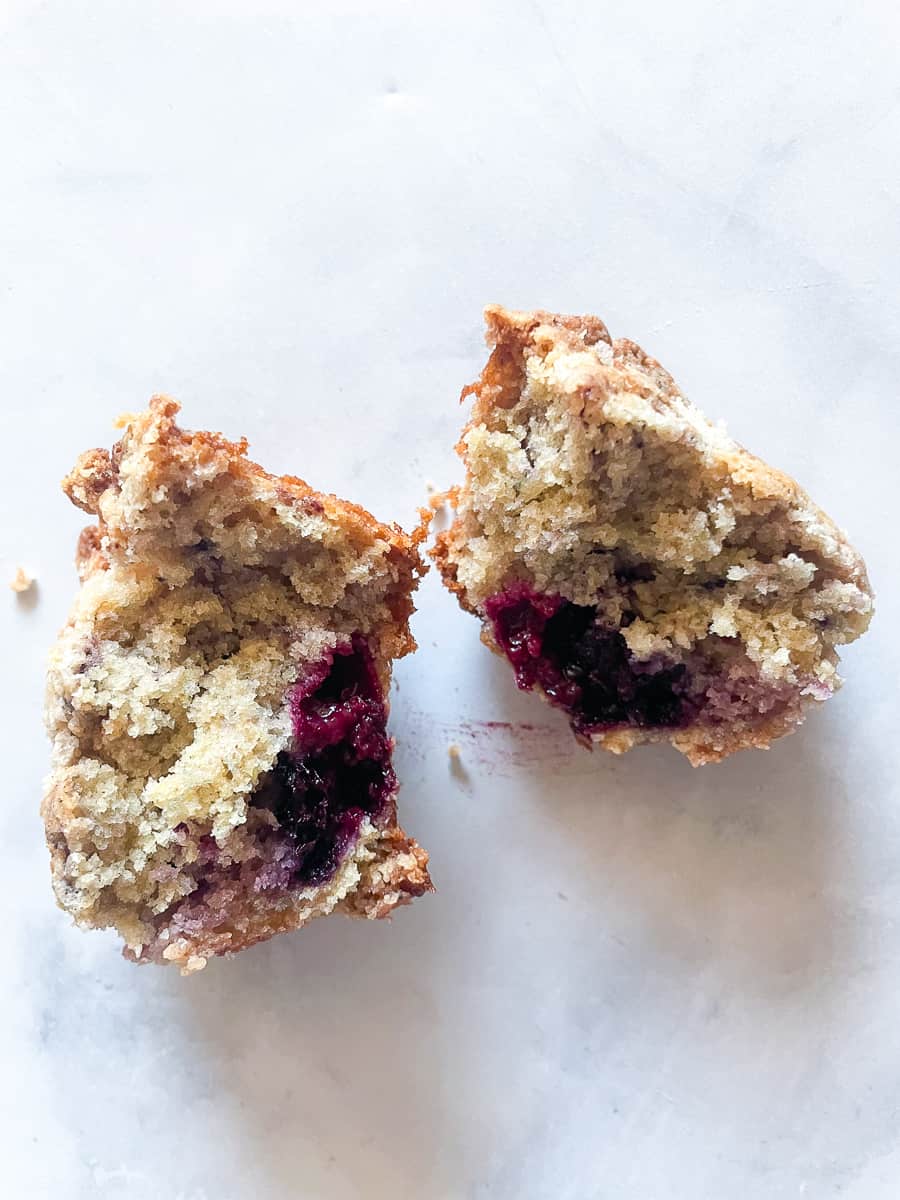 An oat flour blackberry muffin is split in half to show its interior.