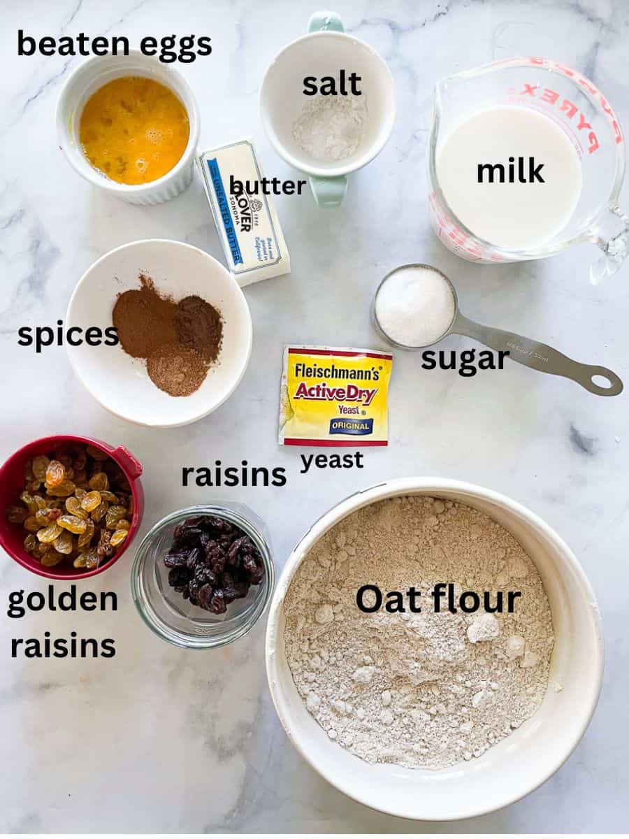 The ingredients for gluten free barm brack are shown: oat flour, raisins, golden raisins, yeast, sugar, butter, milk, eggs.