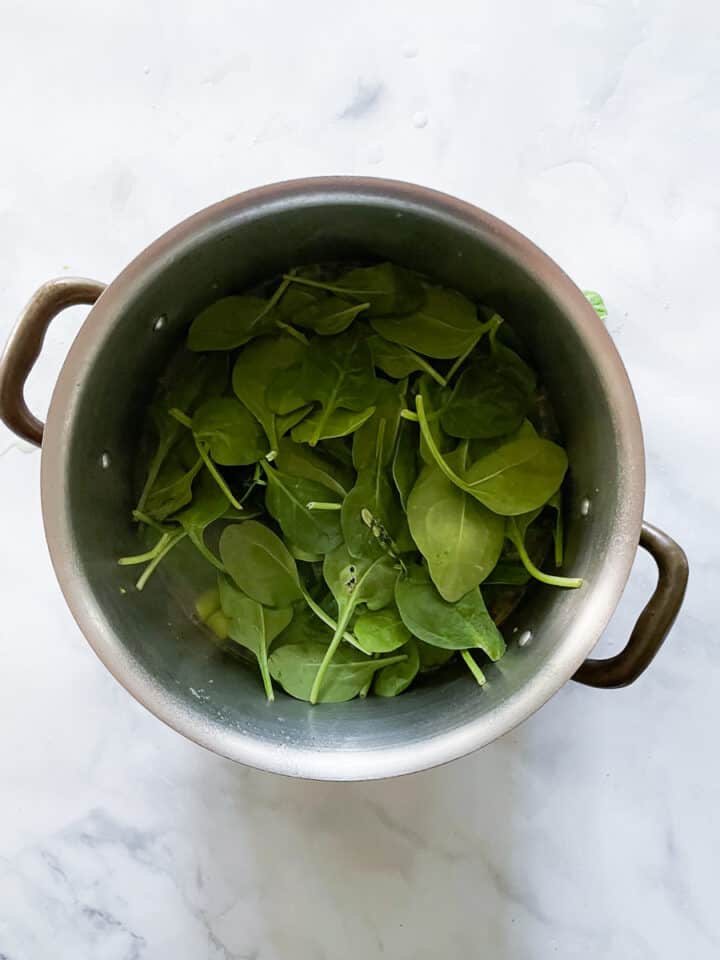 Baby spinach is added to the pot.