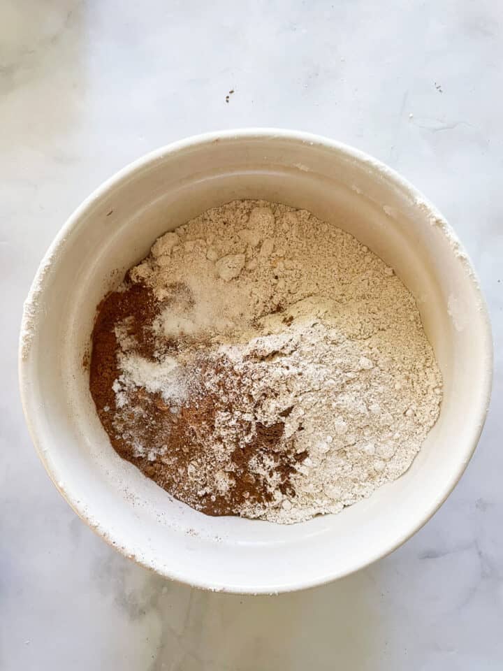 Spices are added to the oat flour in a bowl.