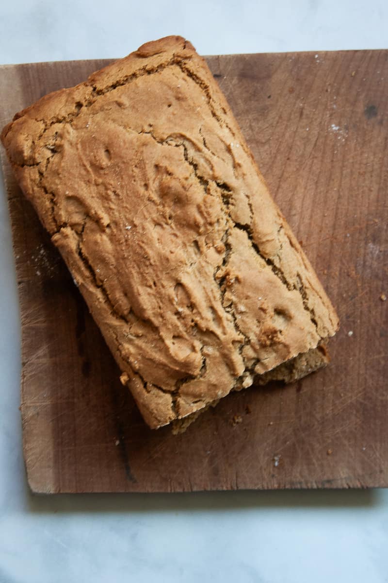 A loaf of gluten free Irish soda bread on a wooden cutting board.