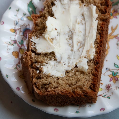 A piece of gluten free Irish soda bread spread with butter on a plate.