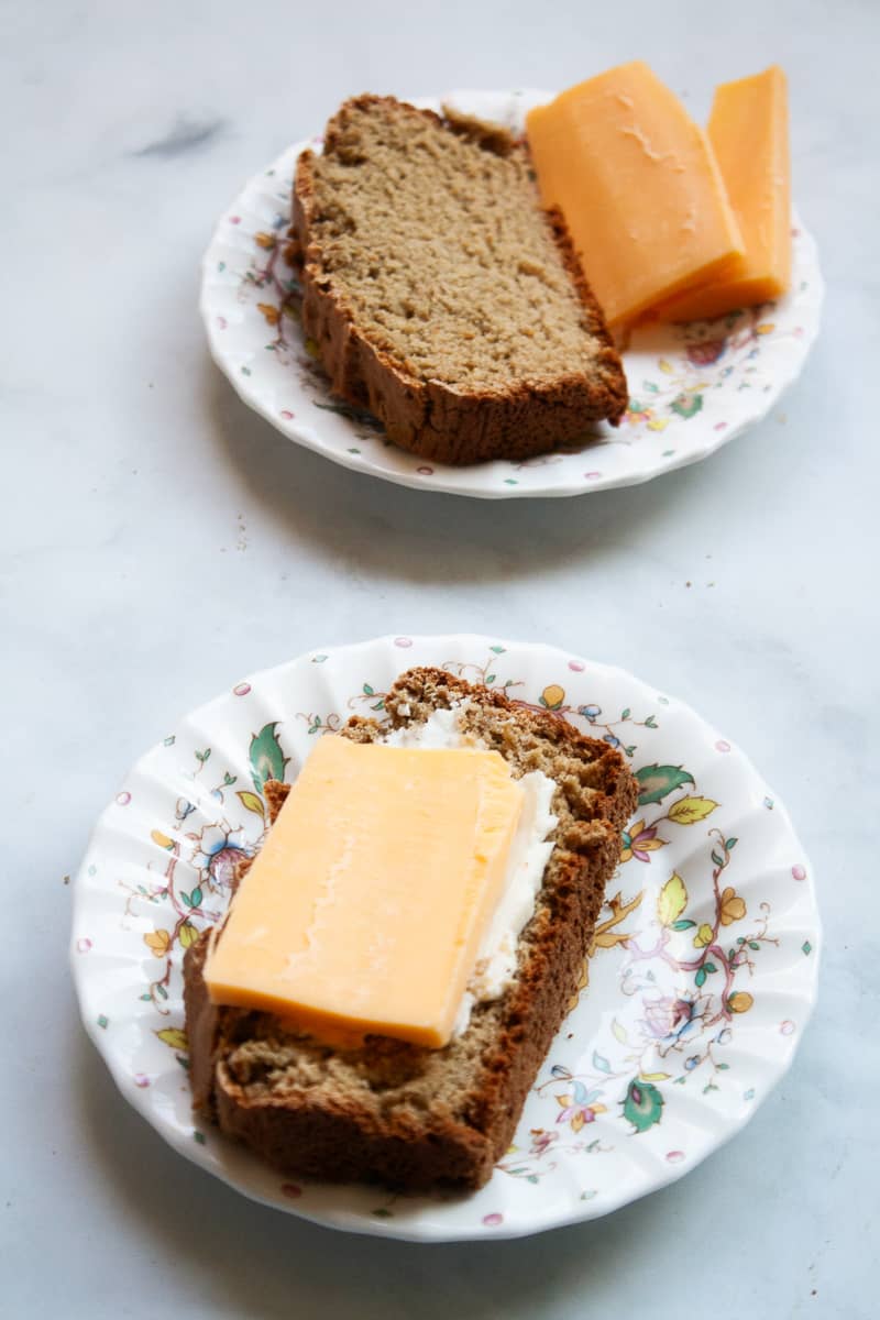 Slices of soda bread on plates with slices of cheddar cheese.