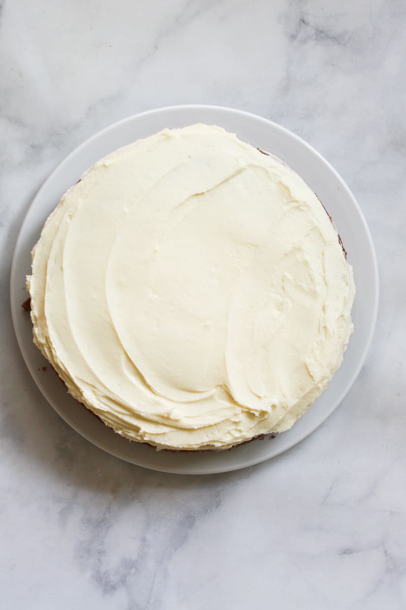 Cream cheese frosting is swirled over a gluten free carrot cake.