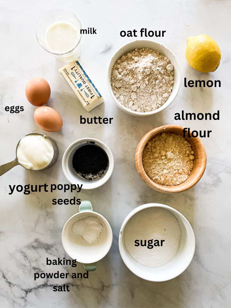 The ingredients for lemon poppyseed muffins are portioned and labelled: eggs, yogurt, poppyseeds, sugar, baking powder, lemon almond flour, oat flour, butter, milk.