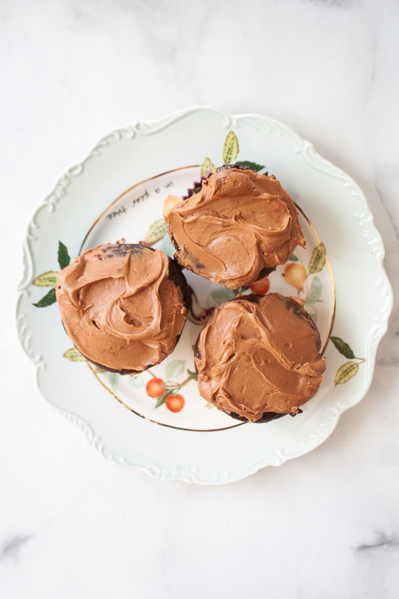Three gluten free chocolate cupcakes on a decorative plate.