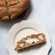 A loaf of gluten free soda bread and a slice of bread and butter on a plate.