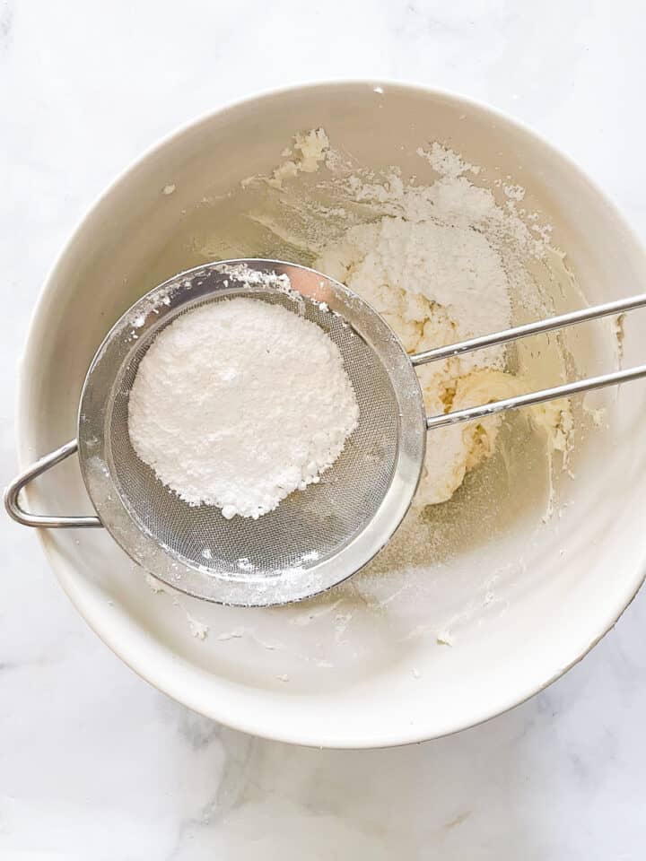 Powdered sugar is sifted into the frosting.