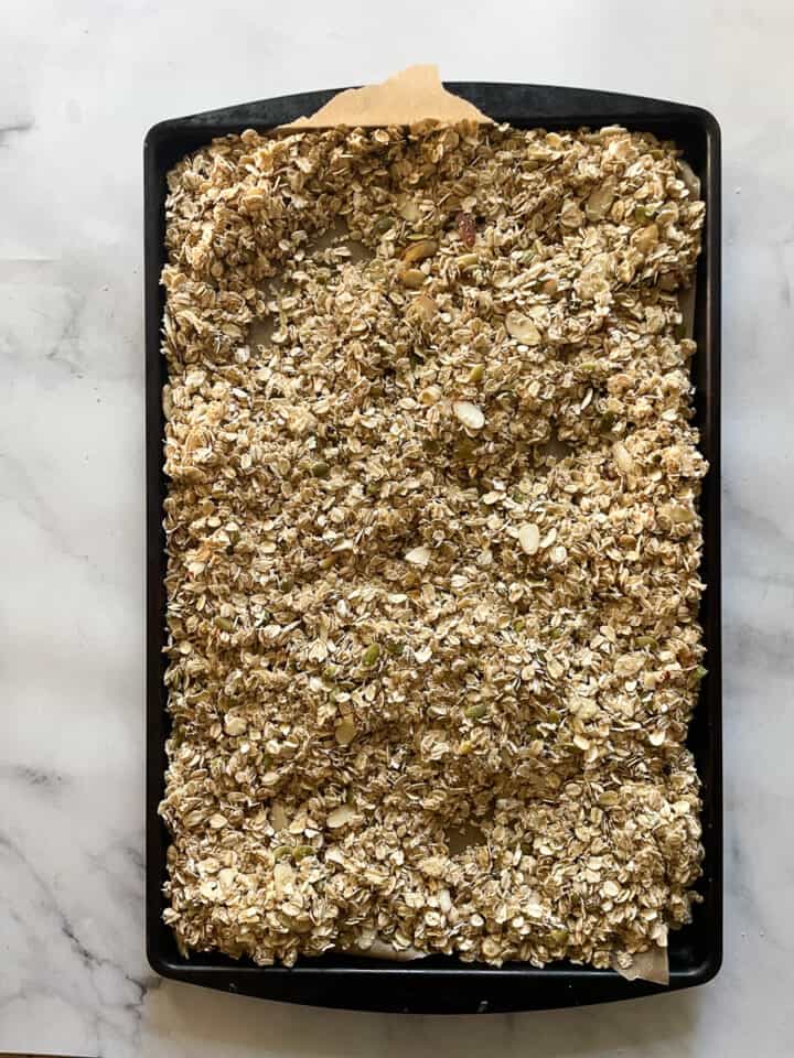 The granola is spread out on a baking sheet.