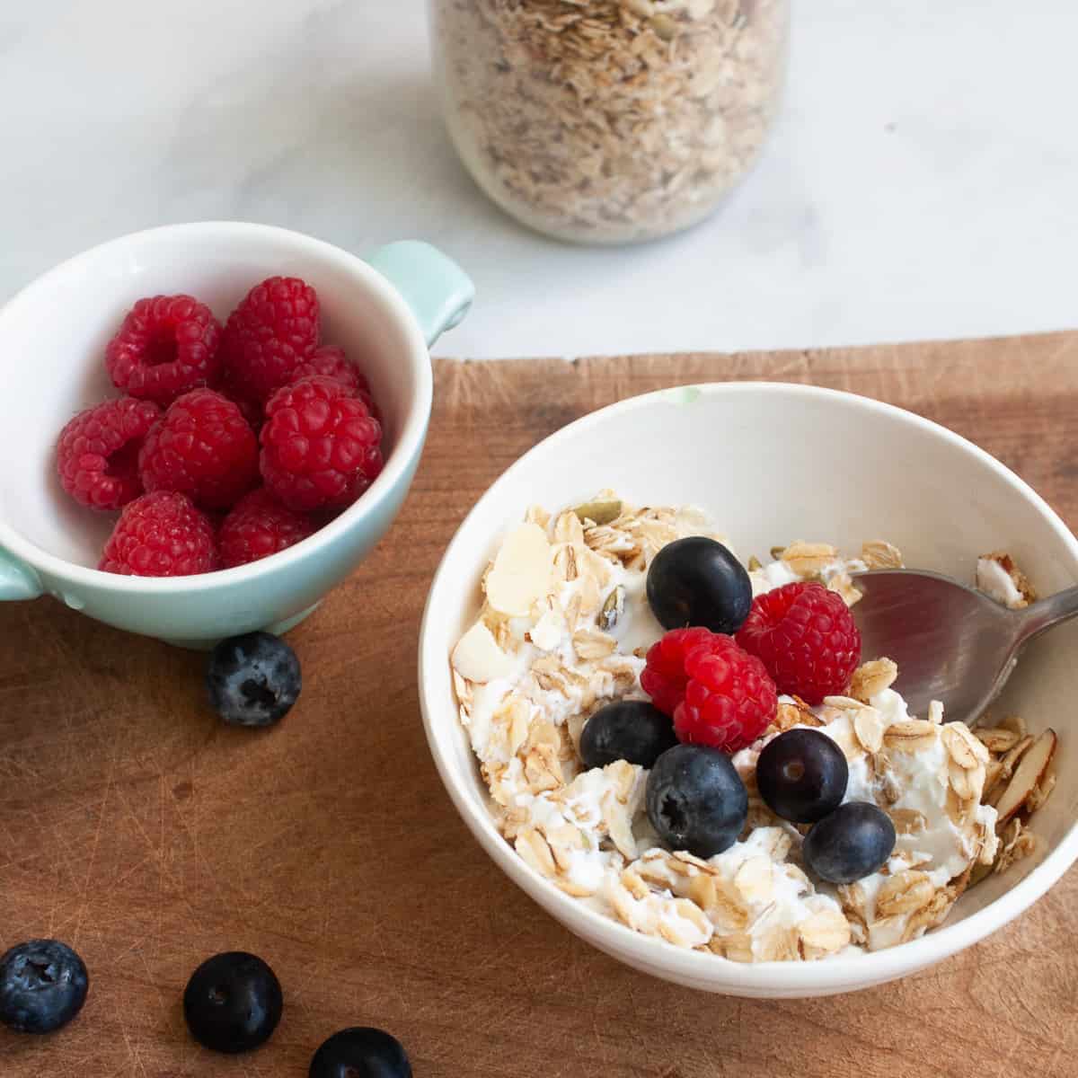 A bowl of gluten-free granola and yogurt topped with raspberries and blueberries.