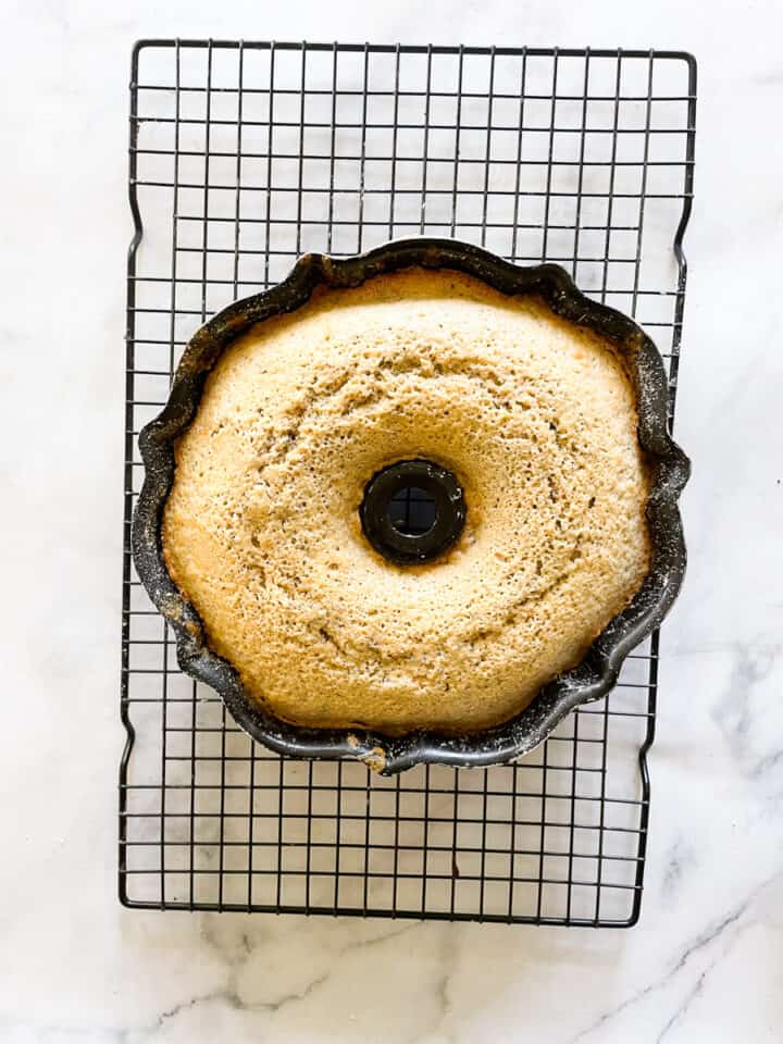 The lemon and poppyseed cake cools in its pan on a rack.