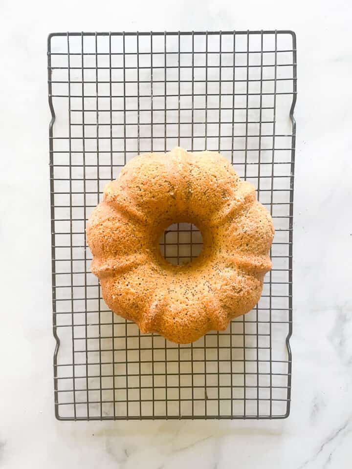 The lemon and poppyseed cake cools on a rack.