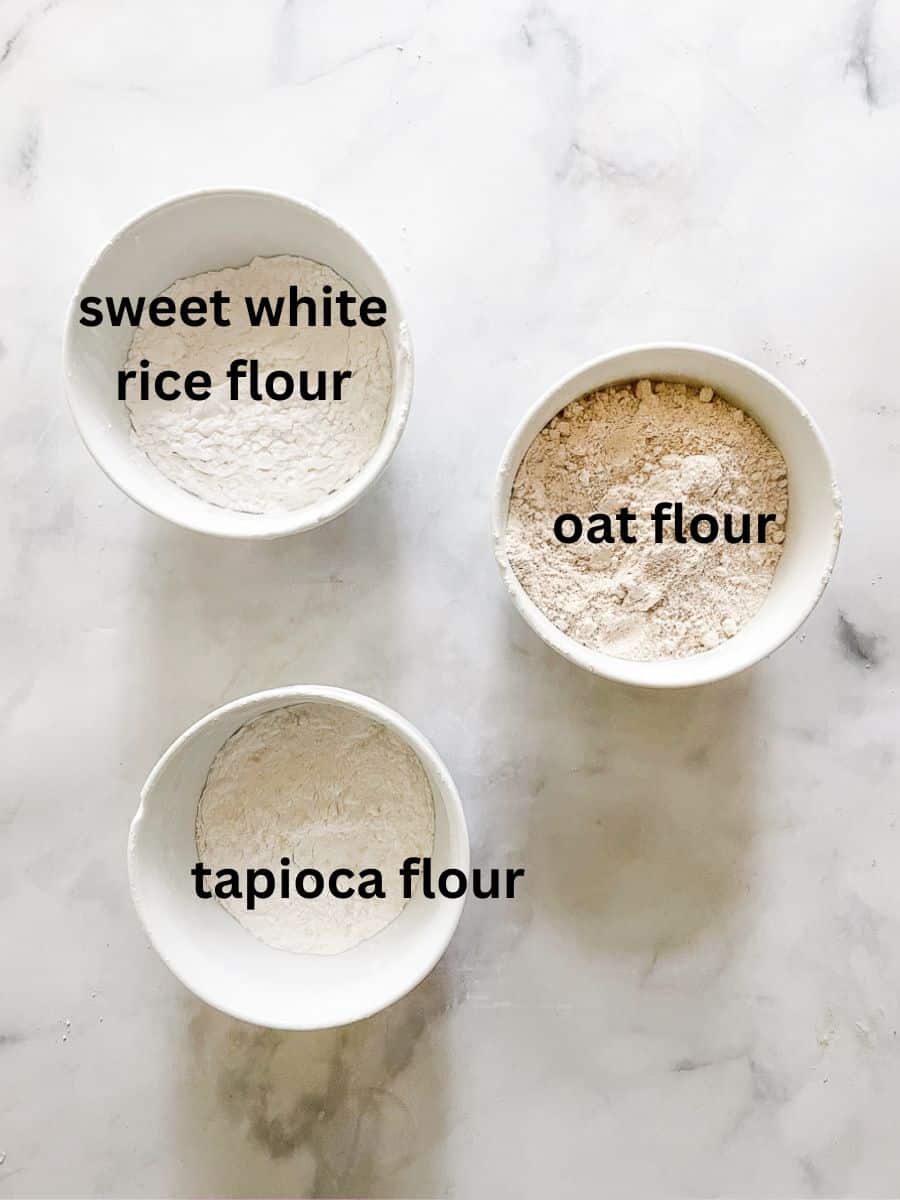 Three bowls of labeled gluten free flours for homemade gluten free flour blend.