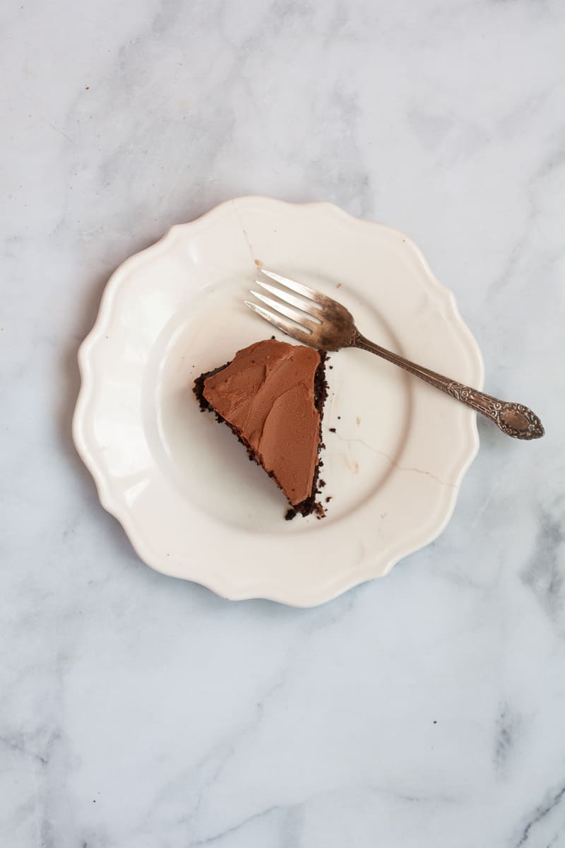 A far away view of a slice of chocolate cake on a plate with a for.