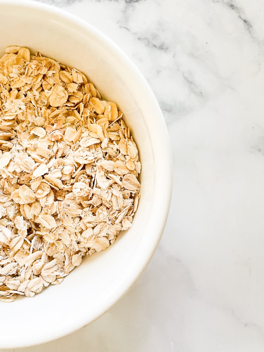 A side view of a white bowl of oats, showing that the answer to are oats gluten free? is yes.