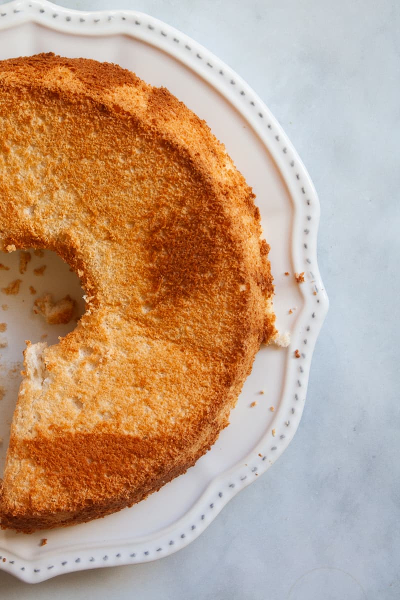 Half of a gluten free angel food cake is shown on a plate.