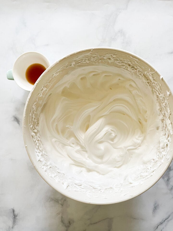 A bowl of beaten egg whites with vanilla next to them.
