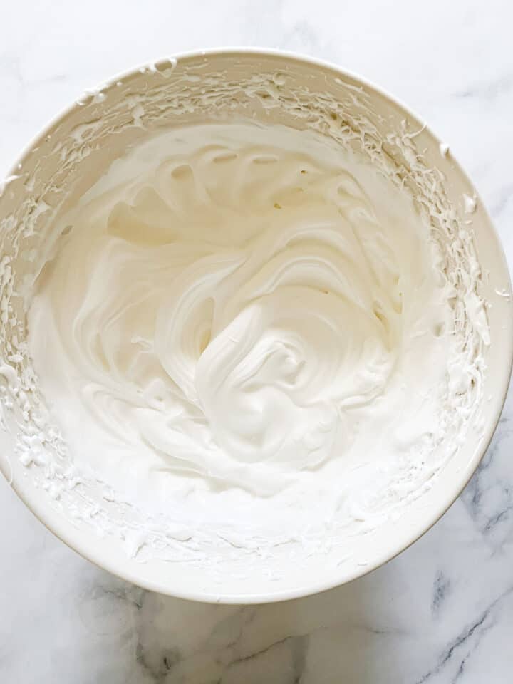Soft peaks form in the beaten egg whites.