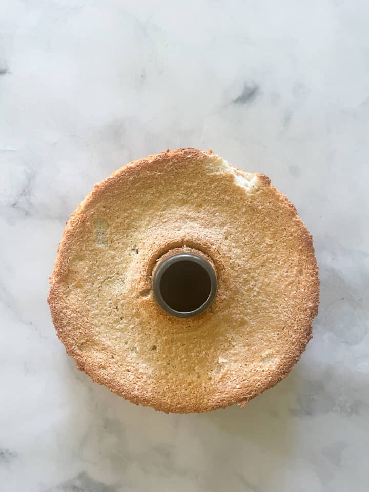 The baked angel food cake in the tube pan with the sides removed.