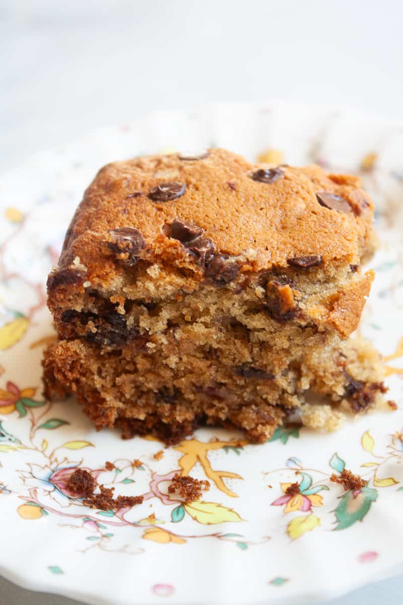 A side view of a piece of fluffy banana chocolate chip cake on a plate.