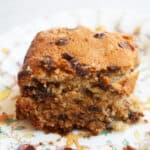 A side view of a piece of fluffy banana chocolate chip cake on a plate.