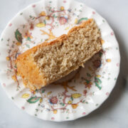A flowered plate with a slice of busy day cake on a white background.