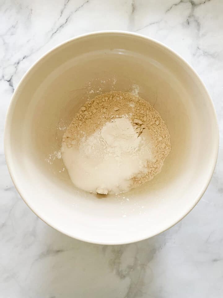 Baking powder and salt are added to the oat flour in a bowl.