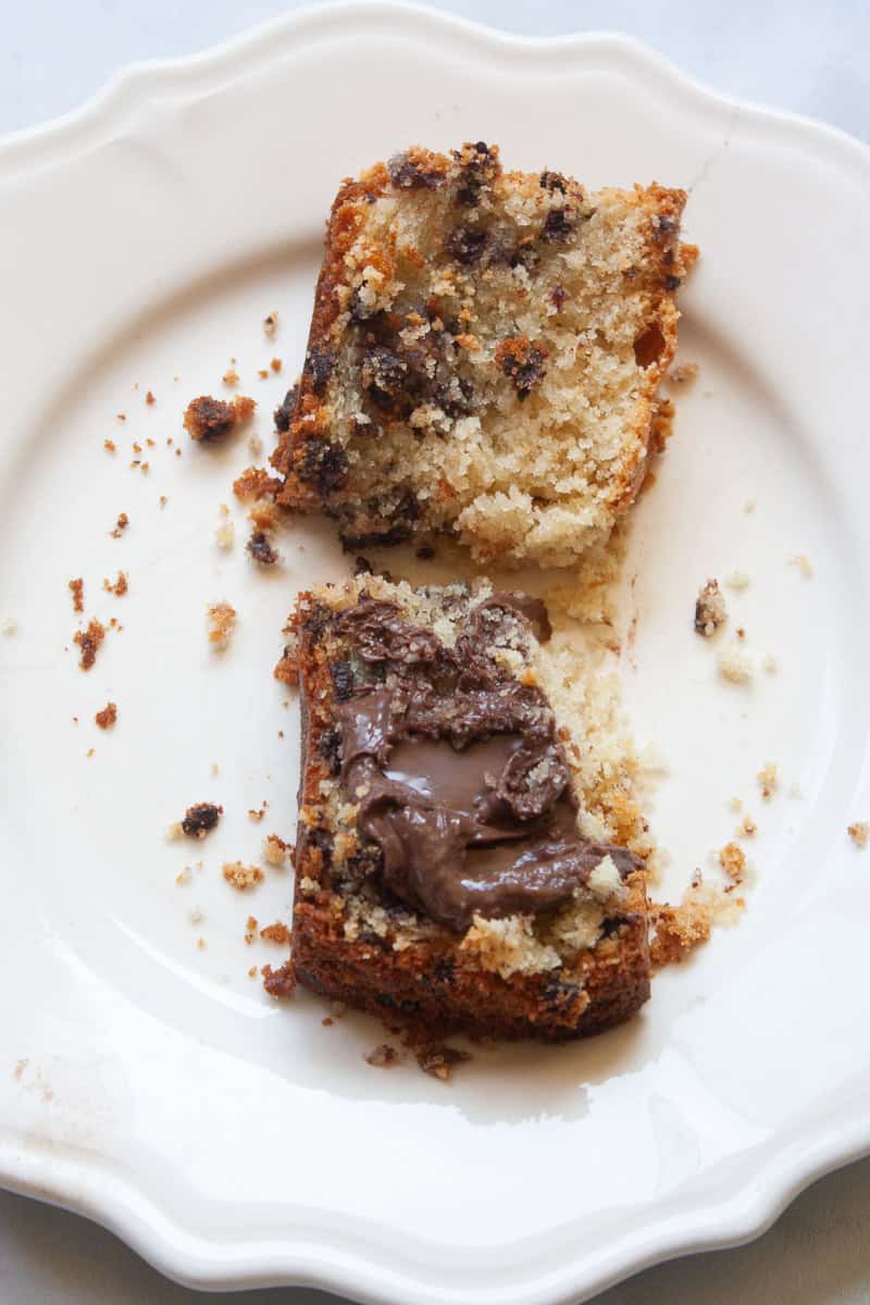 Two halves of a slice of chocolate chip loaf cake, with one half spread with nutella.