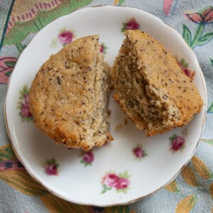 A lemon poppy seed muffin is cut in half on a plate to show its crumb.