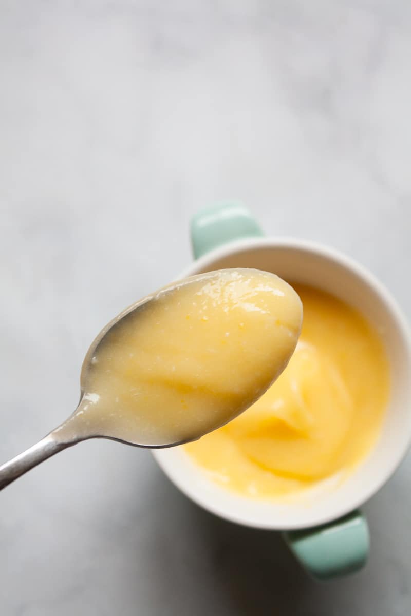 A spoon lifts up a serving of honey lemon curd.