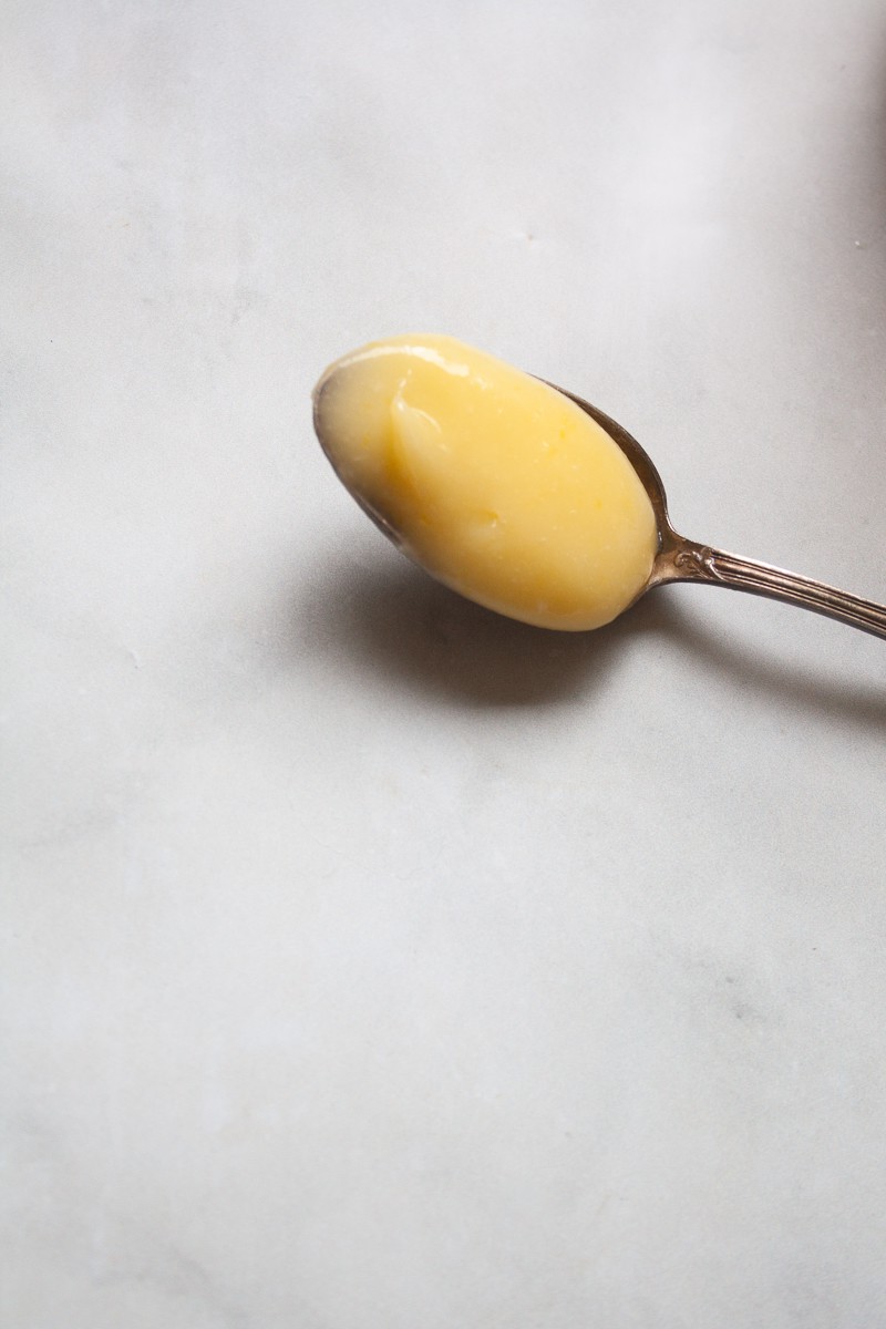 A spoonful of lemon curd on a white background.