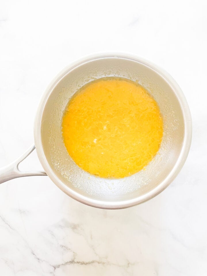 The cooking lemon curd in a stainless steel bowl.
