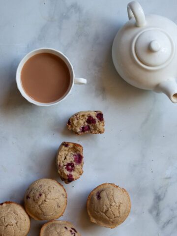 Raspberry muffins, one split in half, and a cup of tea.