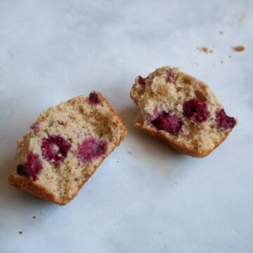 An oatmeal raspberry muffin is split in half.