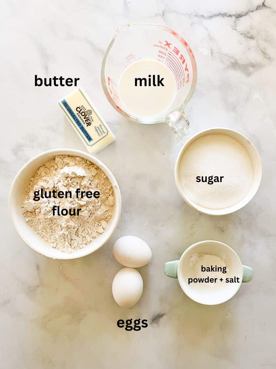 The ingredients for gluten free butter cake are shown portioned out and labelled: gluten free flour, sugar, egg, butter, milk, baking powder, and salt.
