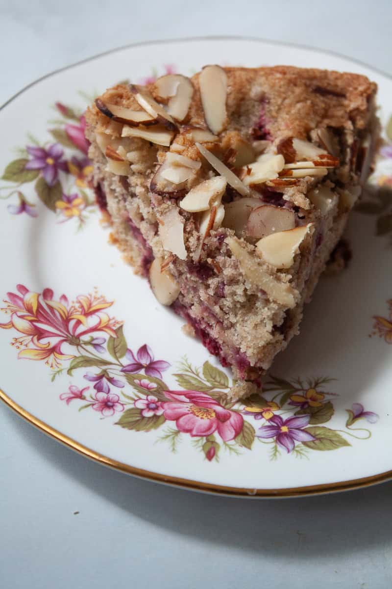 A slice of raspberry almond cake on a flowered plate.