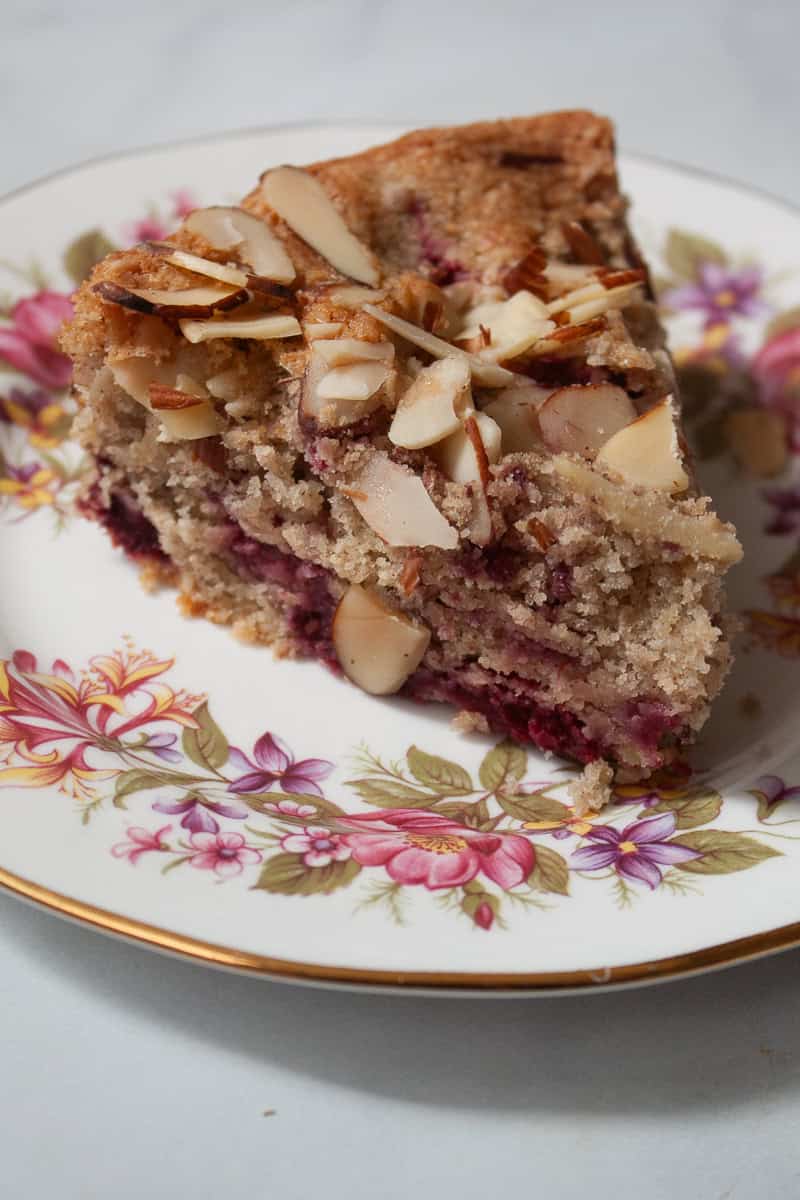 A slice of raspberry almond cake on a flowered plate.