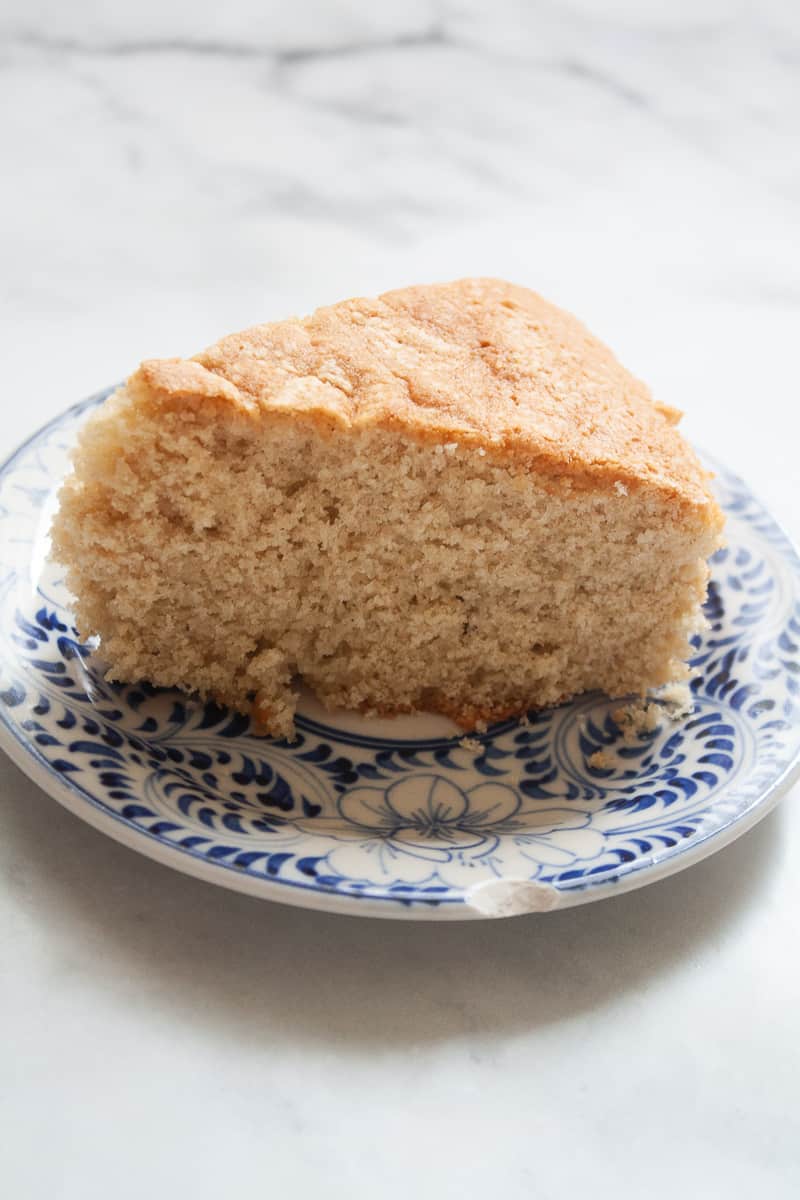 A side view of a piece of oat flour vanilla cake on a blue and white plate.