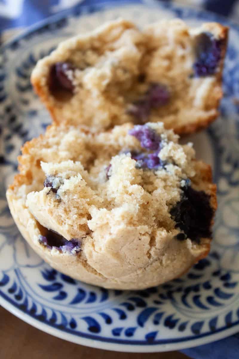 A close up shot shows the tender crumb of an oat flour blueberry muffin.