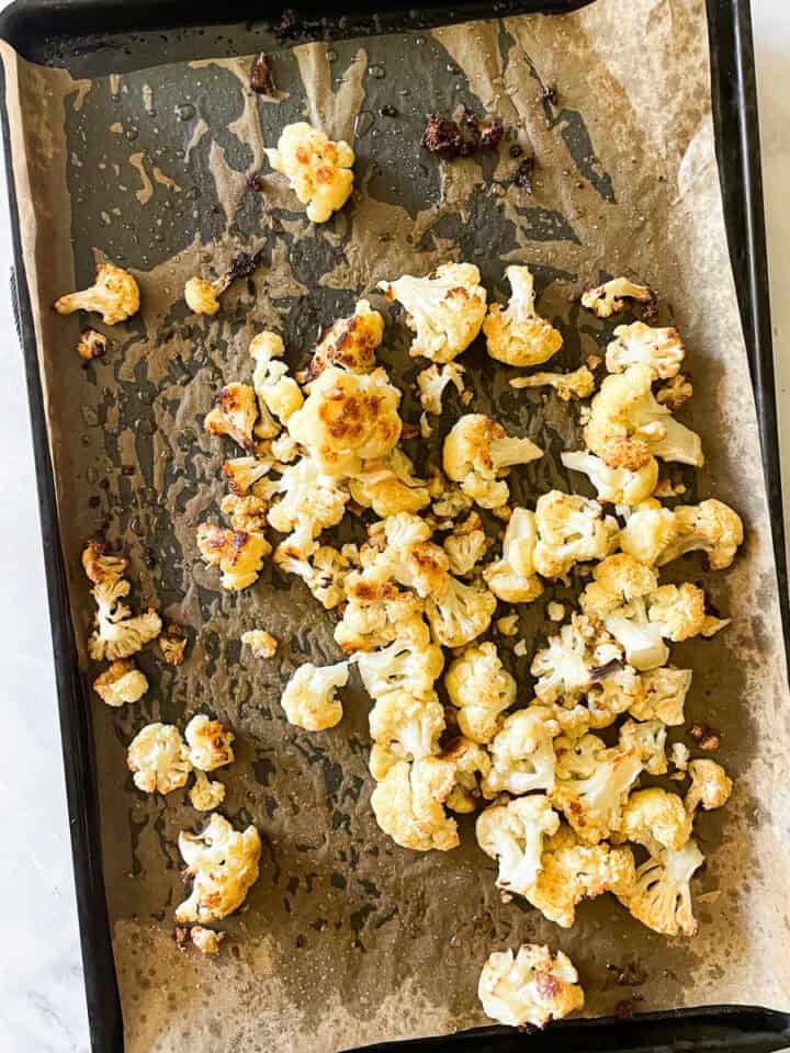 The roasted cauliflower on a baking sheet after being baked.