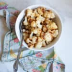 A bowl of roasted cauliflower with a spoon.