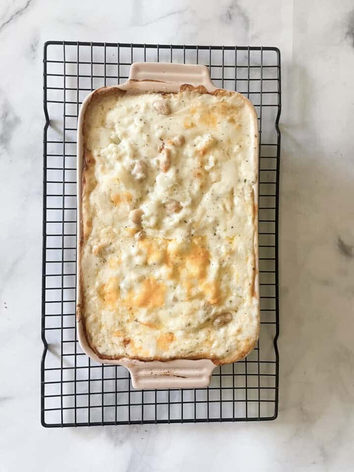 A dish of cooked cauliflower cheese casserole cools on a rack.