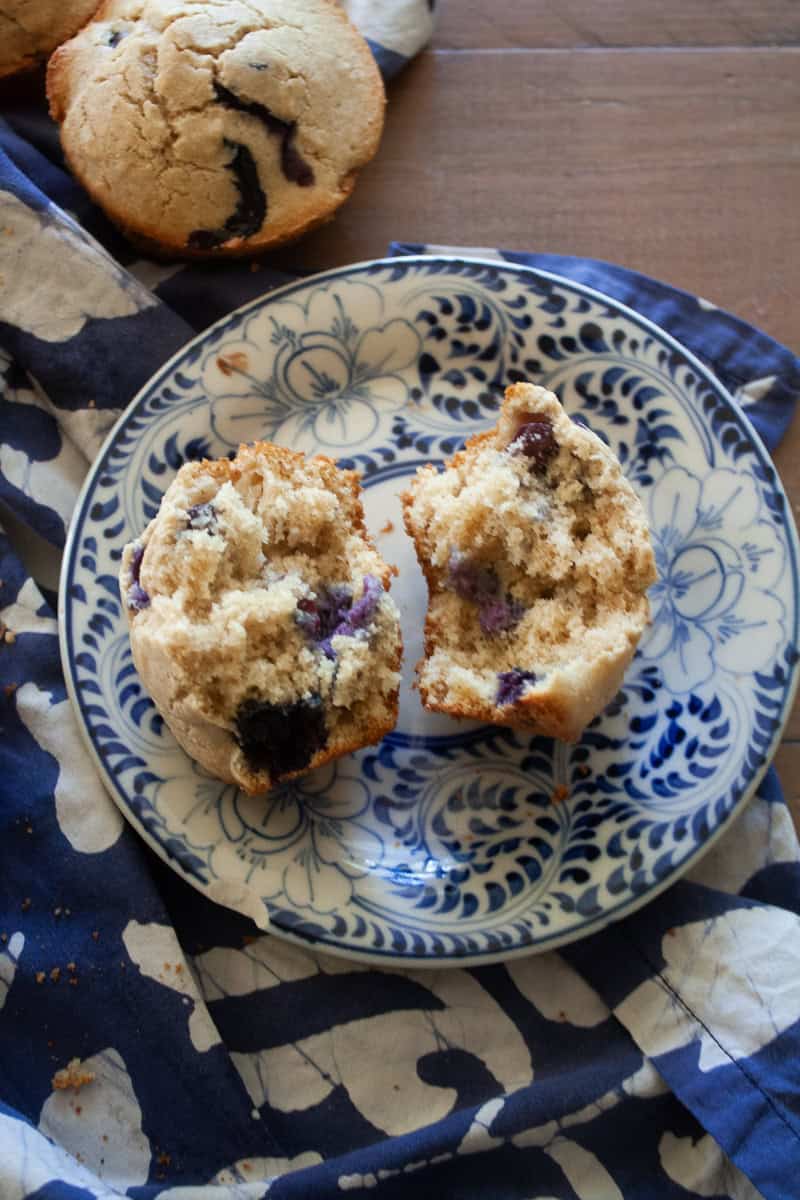 Two halves of a blueberry muffin on a blue and white plate.